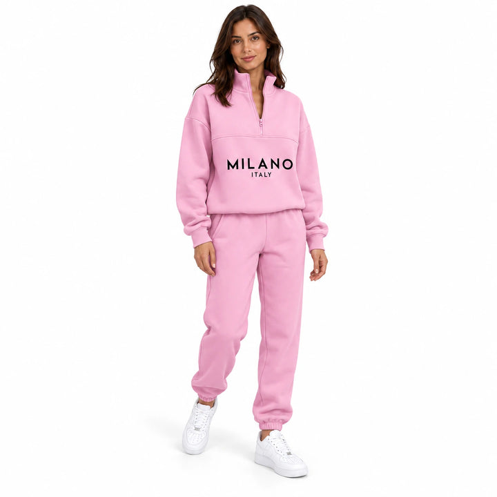 Woman wearing the pink half zip sweatshirt and jogger set in a relaxed studio pose