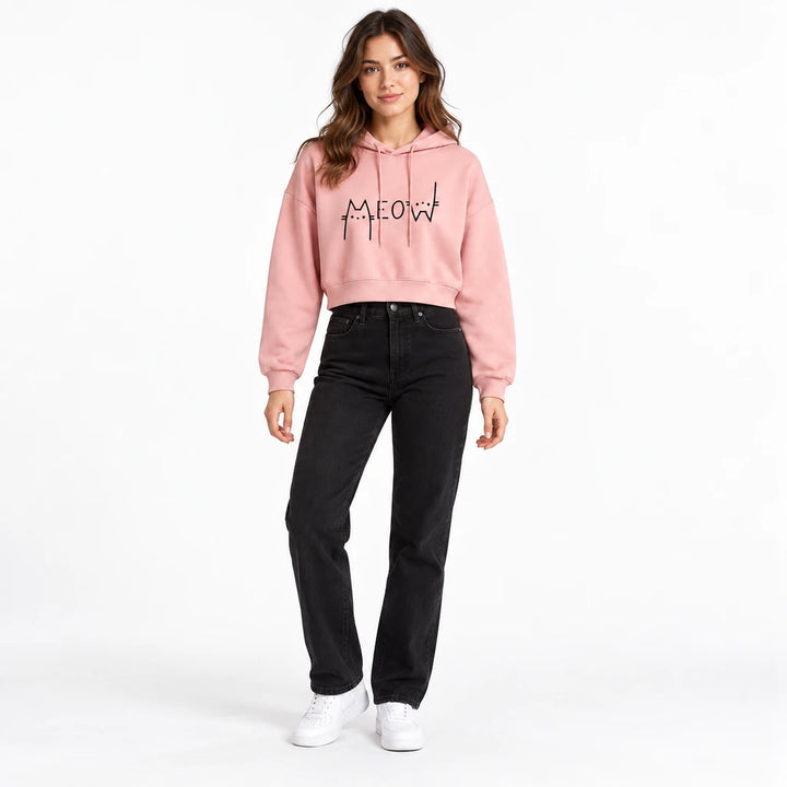 Dusty pink Meow cropped hoodie on a full-body model with black jeans and sneakers, showing the cat print and drawstring hood.