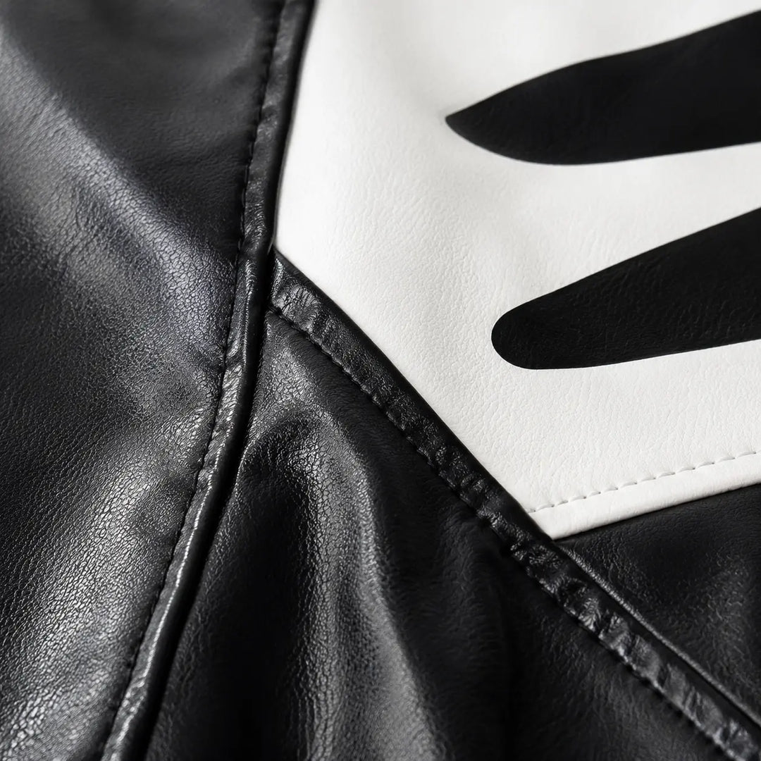Close-up of Black-white colorblock jacket fabric, panel seams, printed graphic area and stitching details for product review.