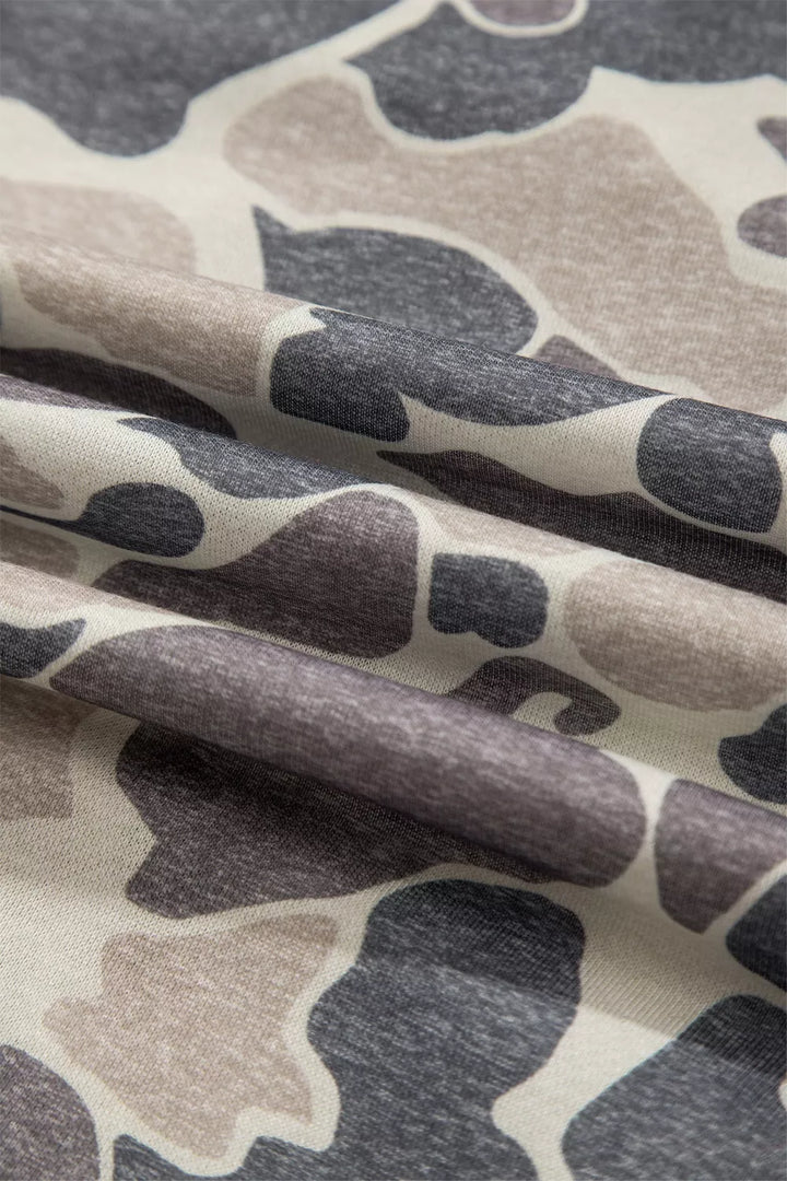 Close view of folded camouflage fabric, showing a fine knit texture and charcoal, taupe and cream colours of the printed top.