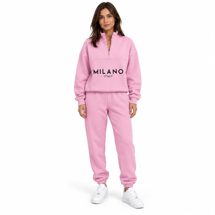 Woman wearing the pink half zip sweatshirt and matching joggers with black MILANO ITALY print