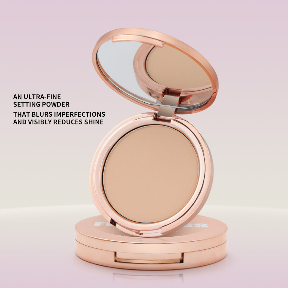 Rose gold compact mirror with beige powder on a light pink background
