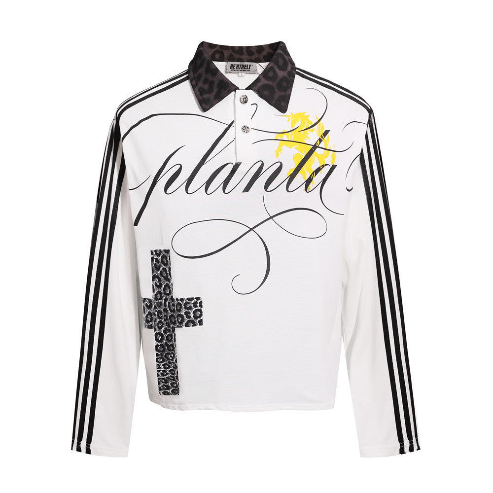 White collared polo shirt seen from the front, featuring black script lettering, long striped sleeves and cross print detail.