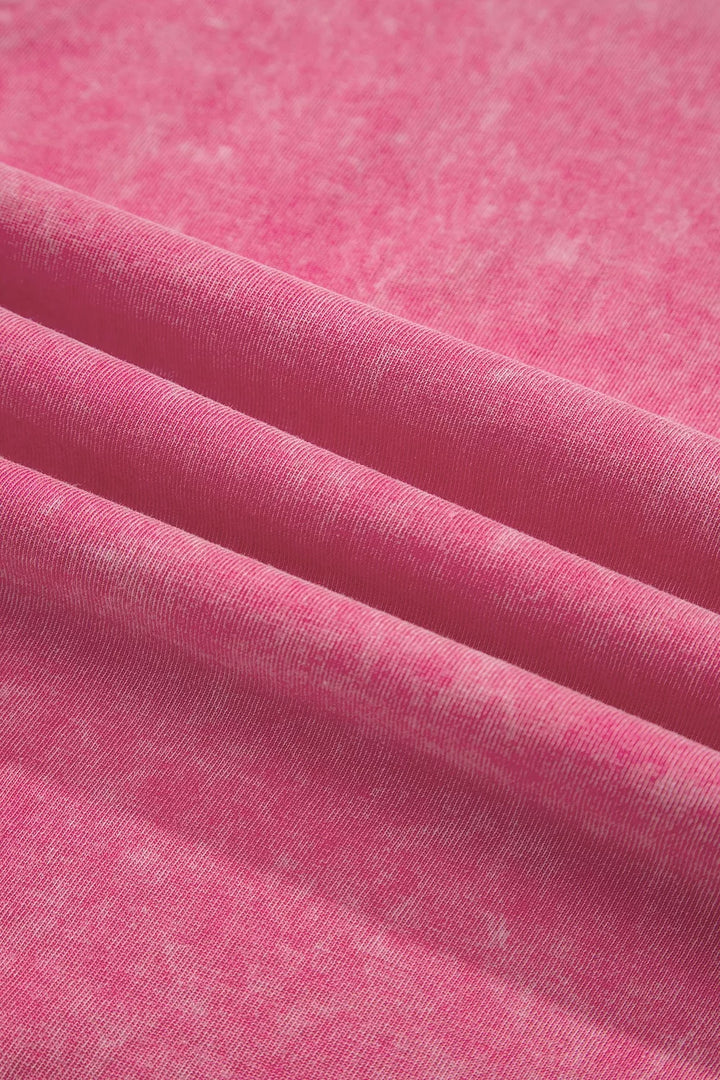 A close-up of pink fabric with a soft, slightly mottled texture, draped in diagonal folds.