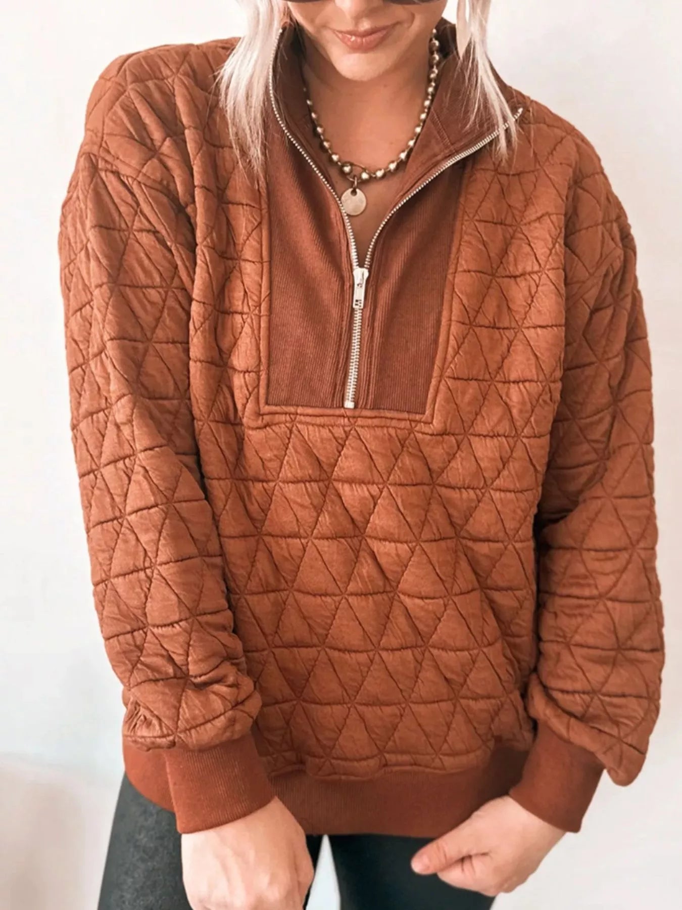 Close-up diamond quilted texture on loose half-zip sweatshirt matte gold zipper detail