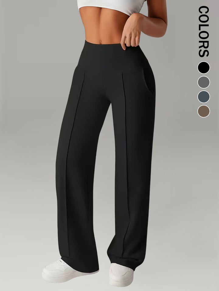 Supplier front view of black athletic trousers with a broad waistband, curved side pockets, front pleats and long loose legs.