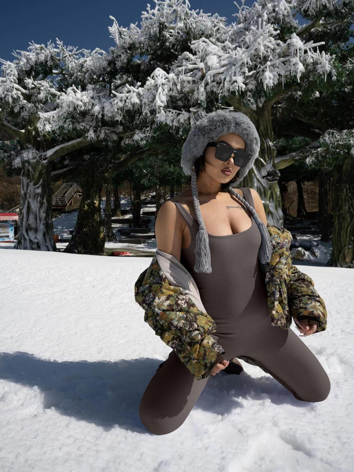 Person in winter clothing posing in the snow with trees in the background