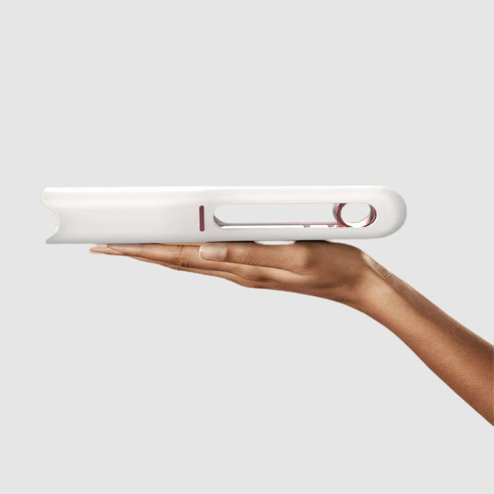 Hand holding a white electronic device with visible branding on a light gray background