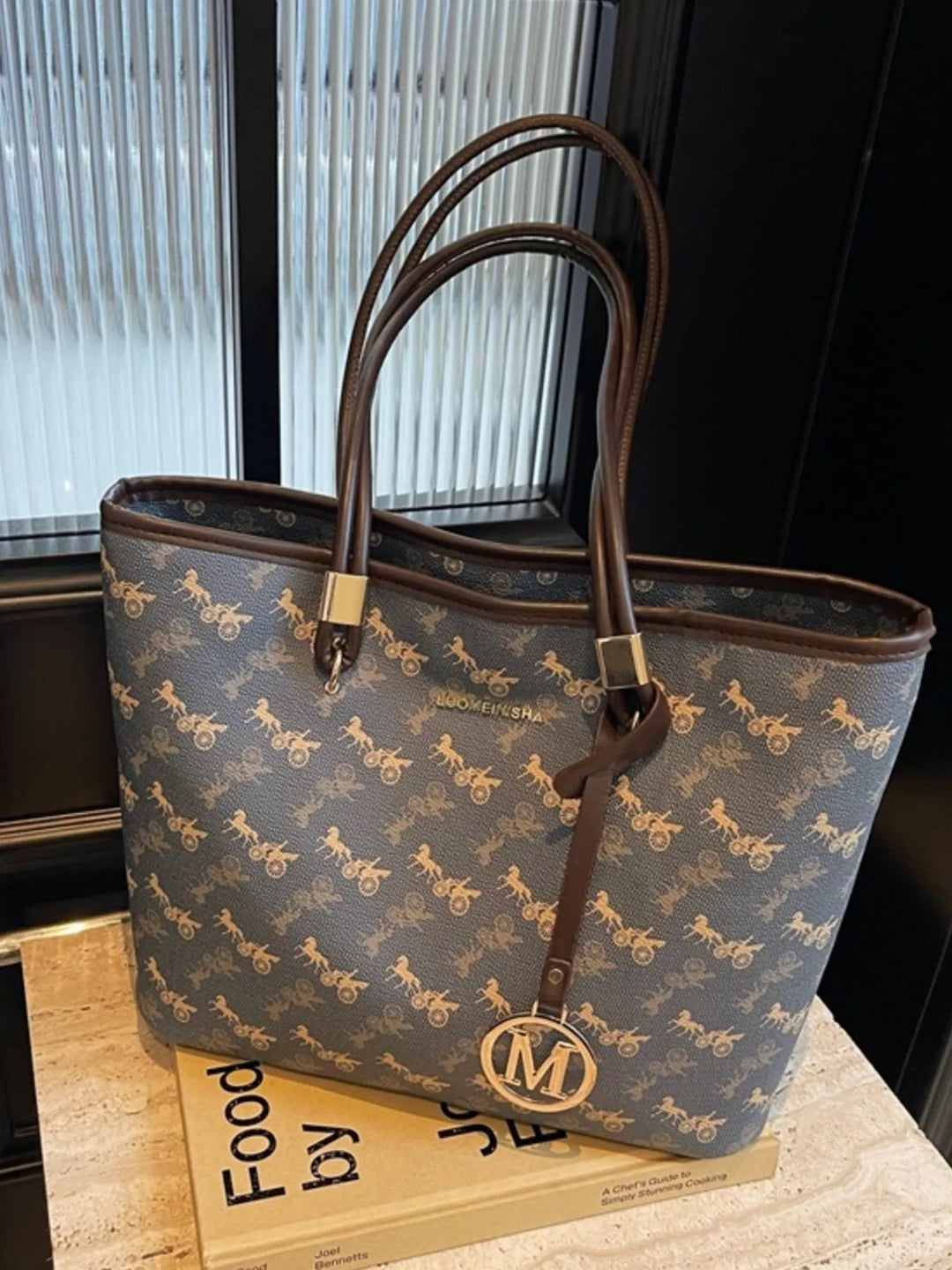 Side angle of large shoulder tote showing structured shape, slim profile, and curved handles.