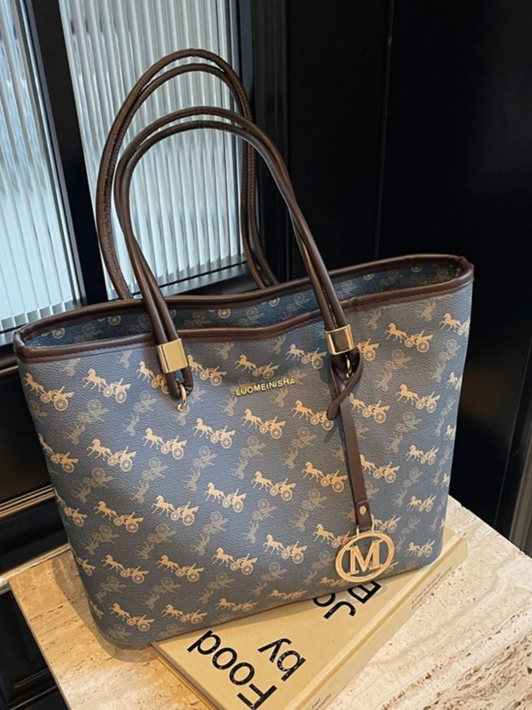 Patterned tote bag held by a woman in a cream blazer for a polished office outfit.