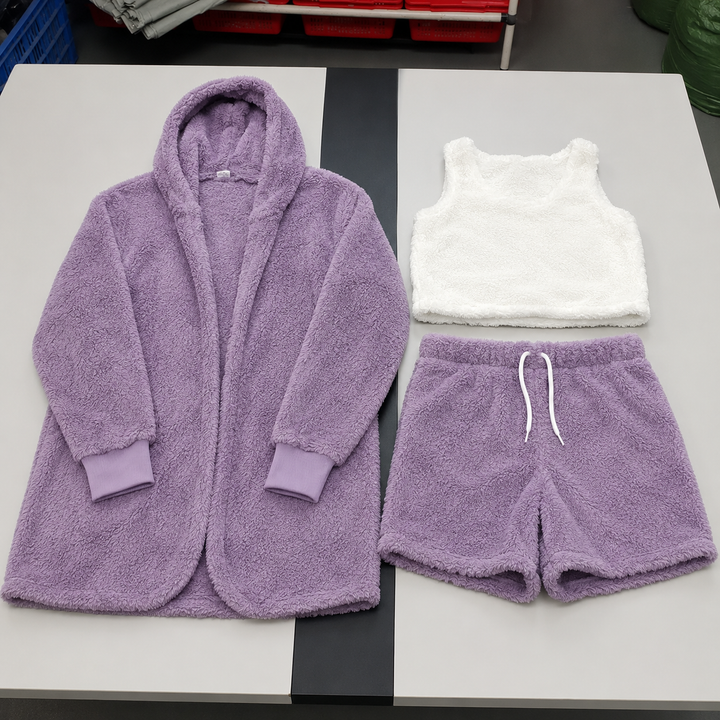 Violet velvet lounge set with cardigan, white crop top and drawstring shorts displayed neatly together across a studio table.