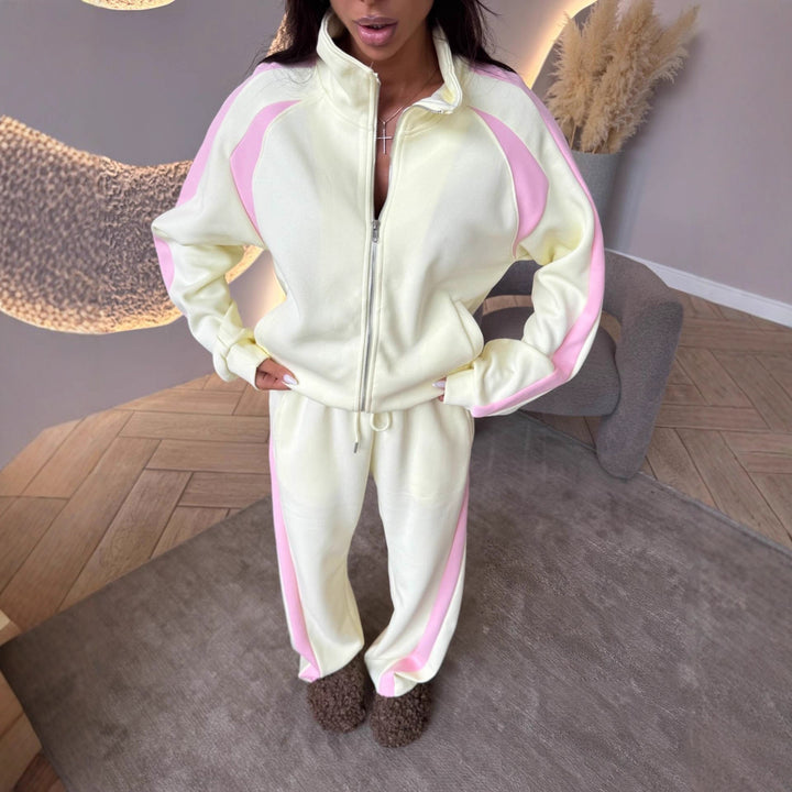 Person wearing a cream and pink tracksuit in a room with wooden flooring and decorative elements.