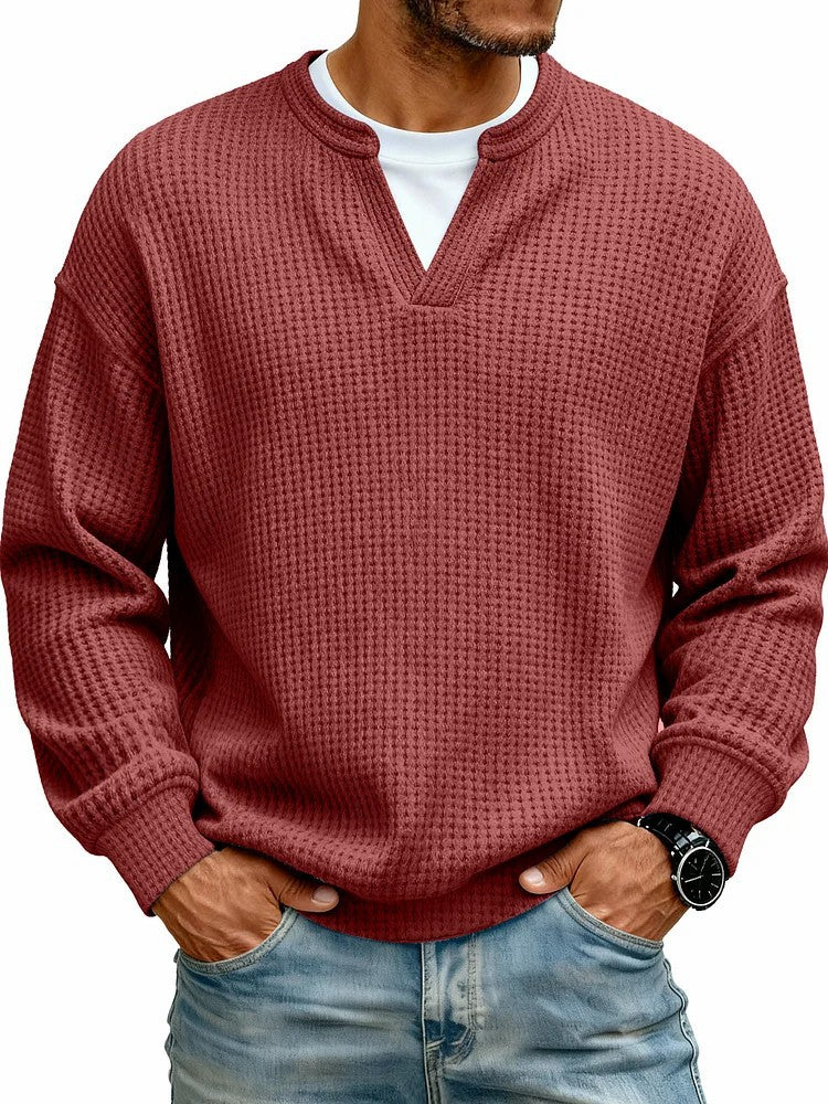Man wearing a textured red sweater over a white shirt with blue jeans on a white background