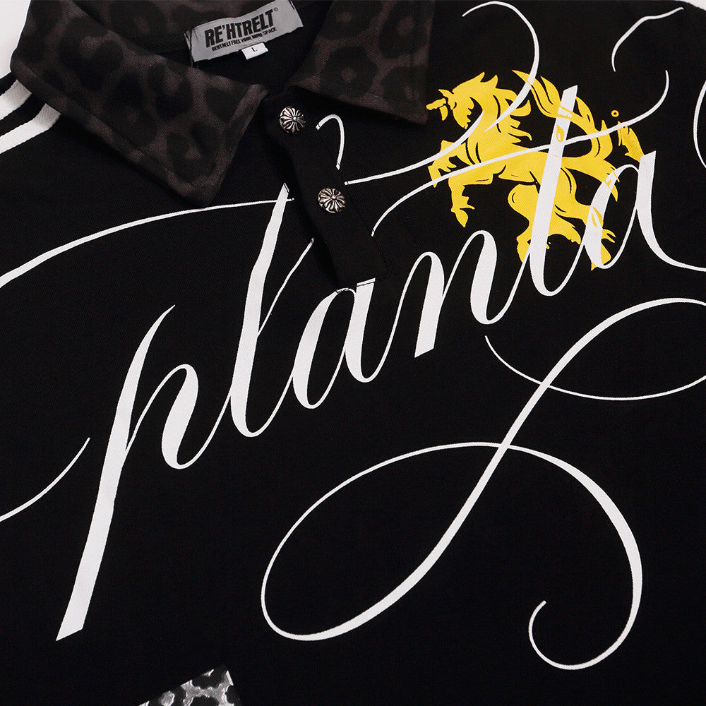 Black collared shirt close-up showing two decorative buttons, dark leopard-pattern collar, white script and one yellow motif.