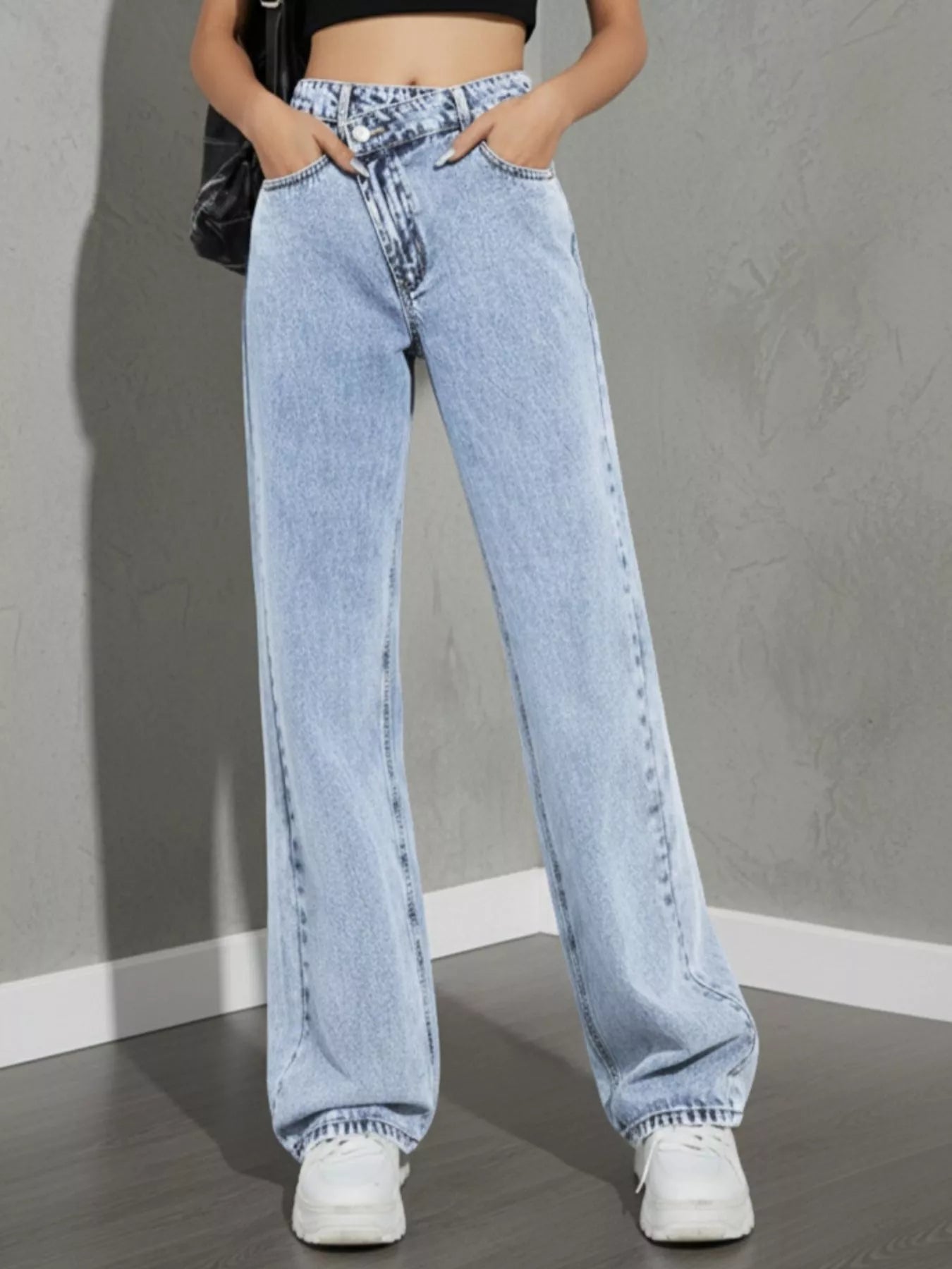 high rise wide leg jeans hem and leg opening detail light wash denim falling over chunky sneakers for long-leg effect
