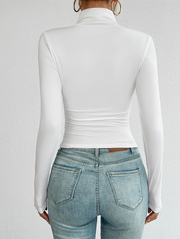 Person wearing a white long-sleeve top and light blue jeans on a plain background