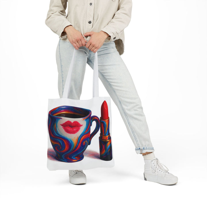 Person holding a tote bag with a colorful design of a coffee cup and lipstick.