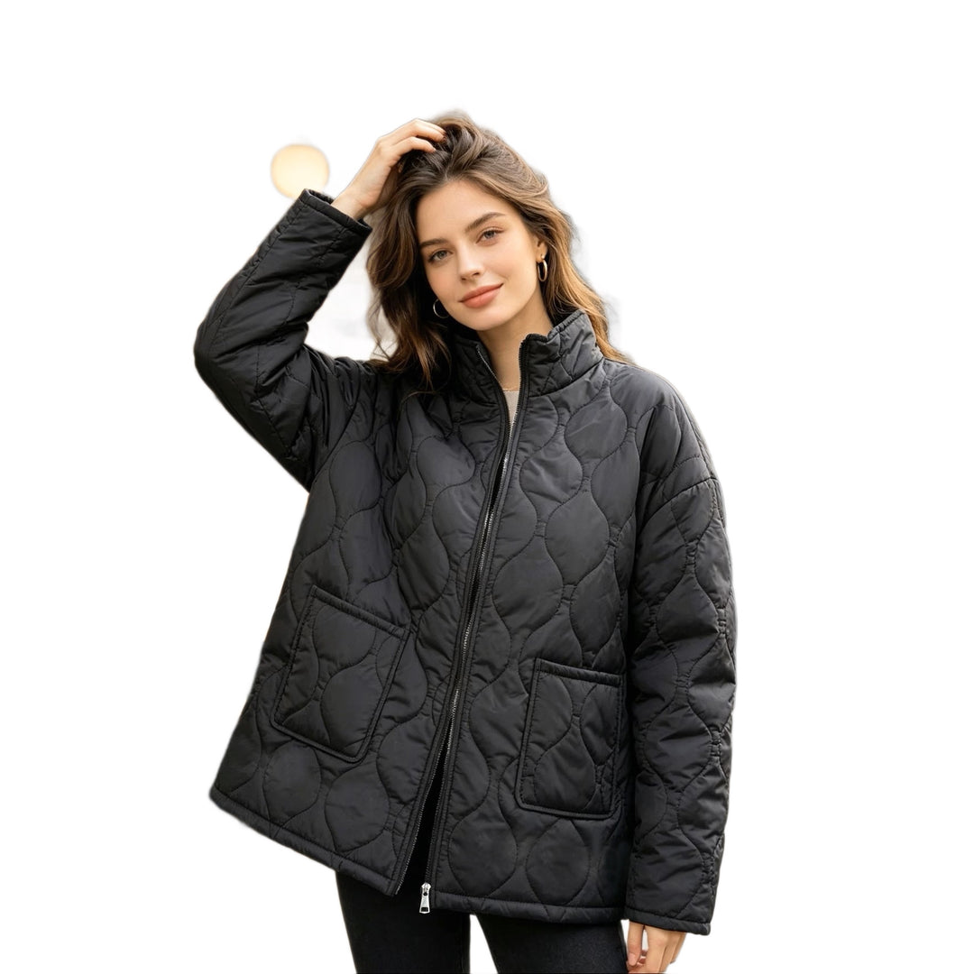 Black quilted coat on a female model on a white background, showing the stand collar, zipper, long sleeves and patch pockets.