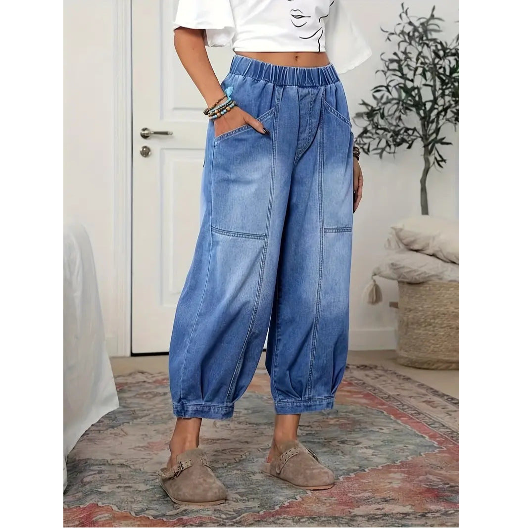 Person wearing blue denim wide-leg pants in a room with a door and plant in the background.