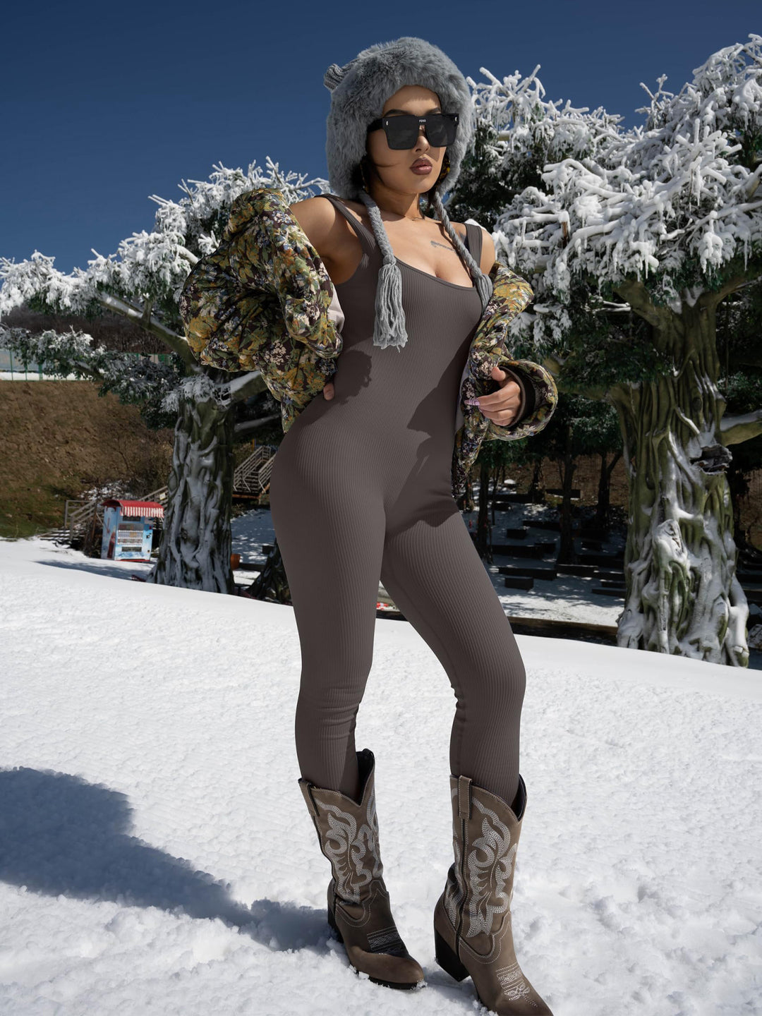 Person in a brown outfit with fur-lined hood and boots standing in snow.