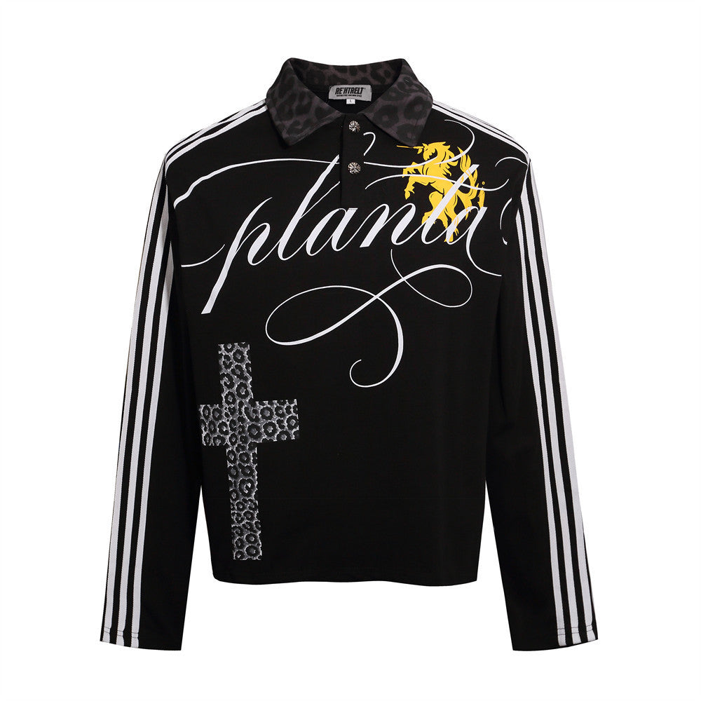Black gothic polo shirt with a leopard-pattern cross, white sleeve stripes, script detail and a patterned collar, front view.