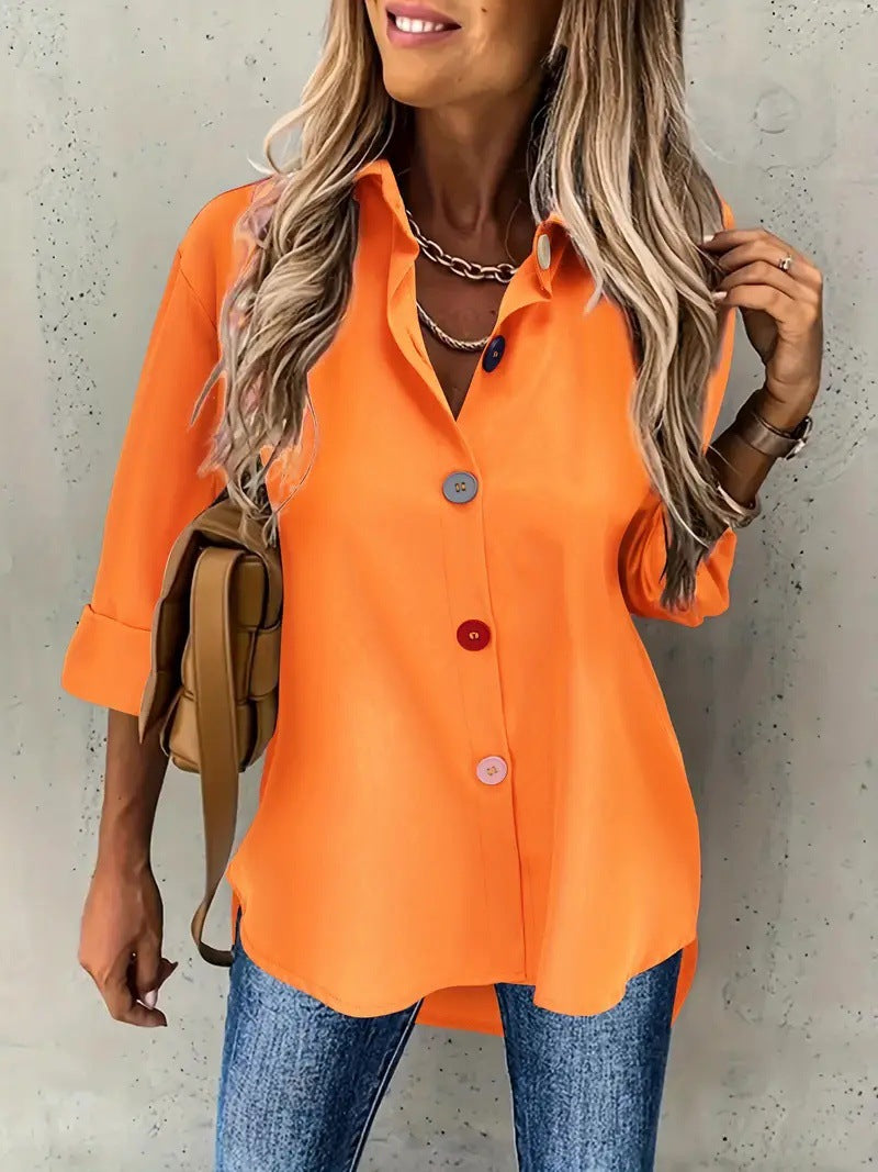 Woman wearing an orange button-up shirt and blue jeans against a neutral background