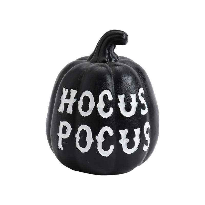 Black decorative pumpkin with white HOCUS POCUS lettering, curved stem and vertical molded grooves on a plain white backdrop.