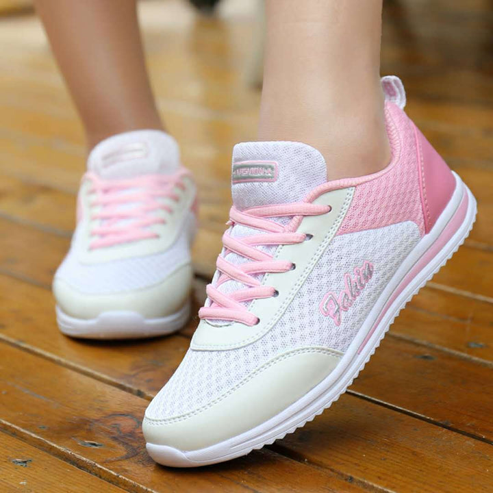 Off-white and pink lace-up shoes worn on wooden steps, showing pale pink laces, white mesh uppers and light pink heel panels.