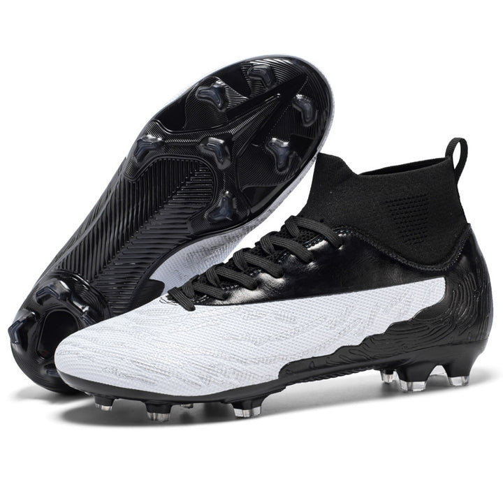 Athlete wearing black and white soccer cleats mid-sprint on outdoor grass training ground
