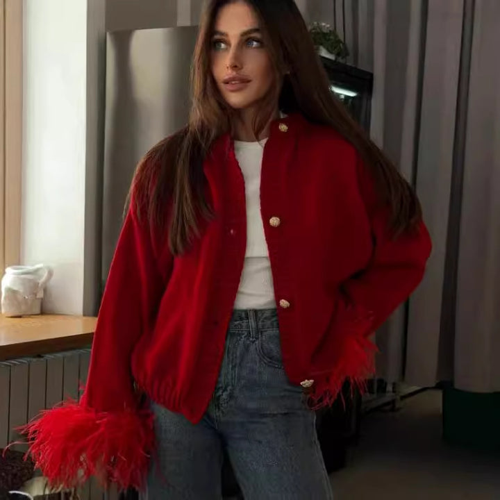 Red feather-trim cardigan worn open over a white top with jeans