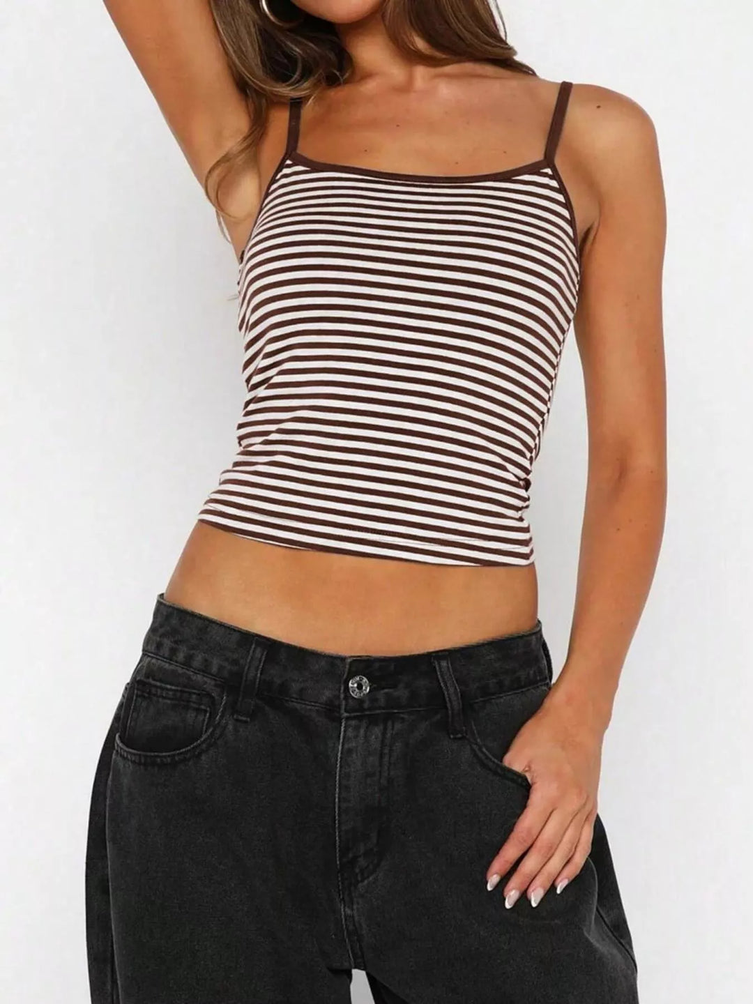 Woman wearing a black and white striped tank top and black jeans on a white background