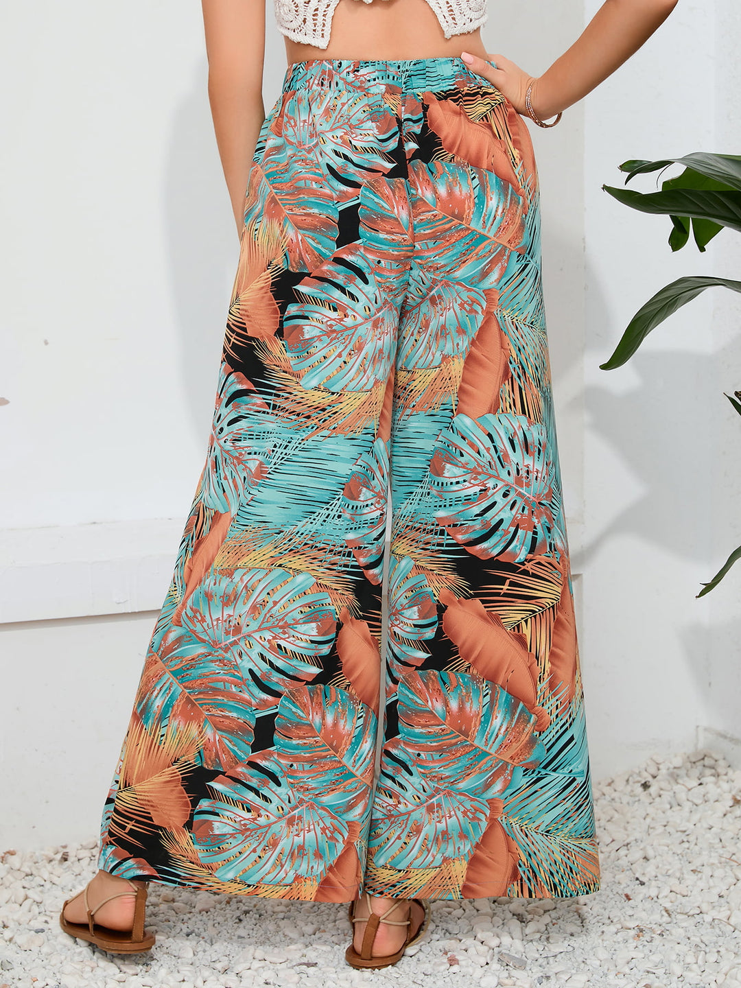 Tropical leaf patterned pants worn by a person on a white background