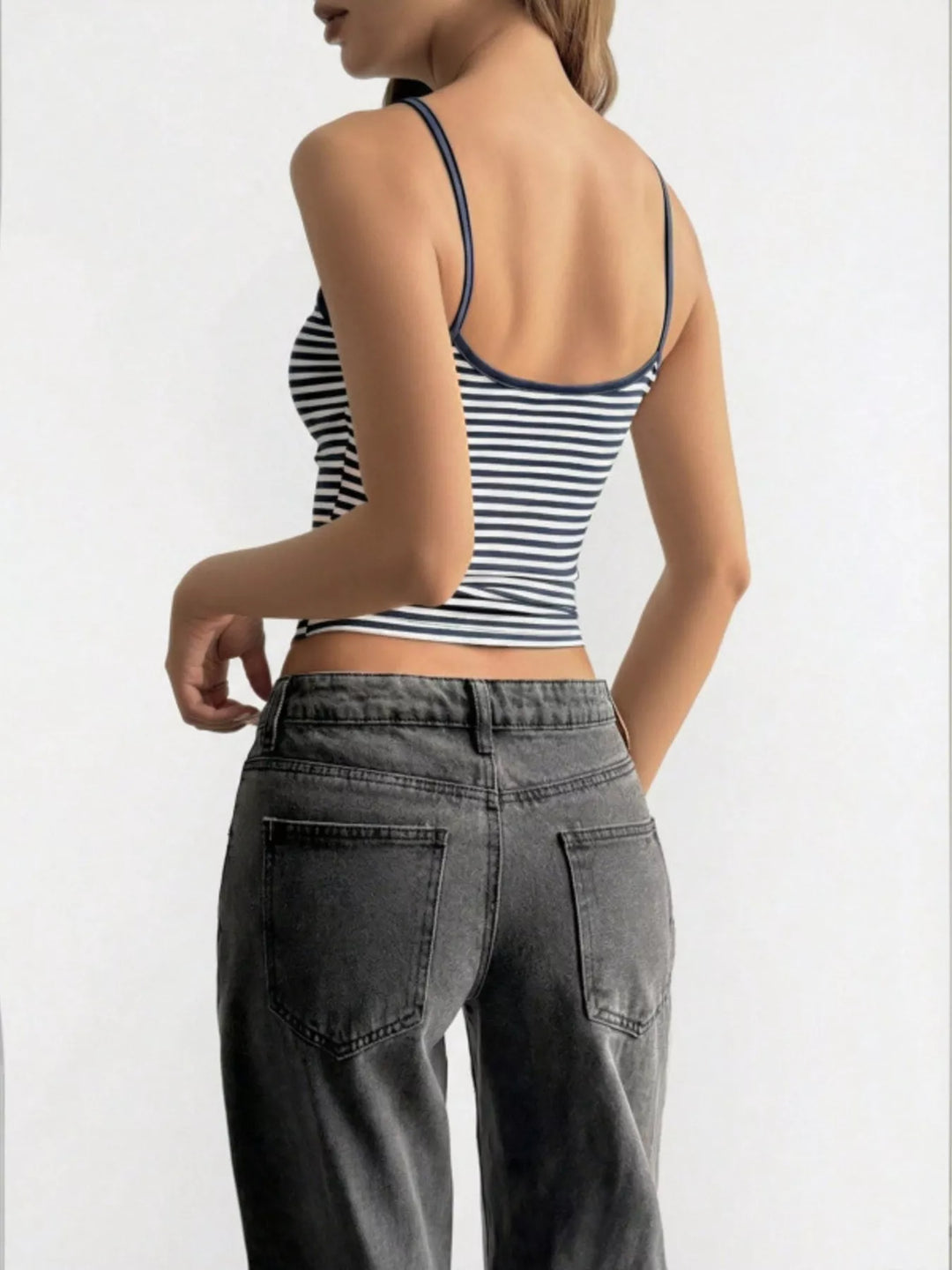 Person wearing a striped crop top and gray pants on a white background