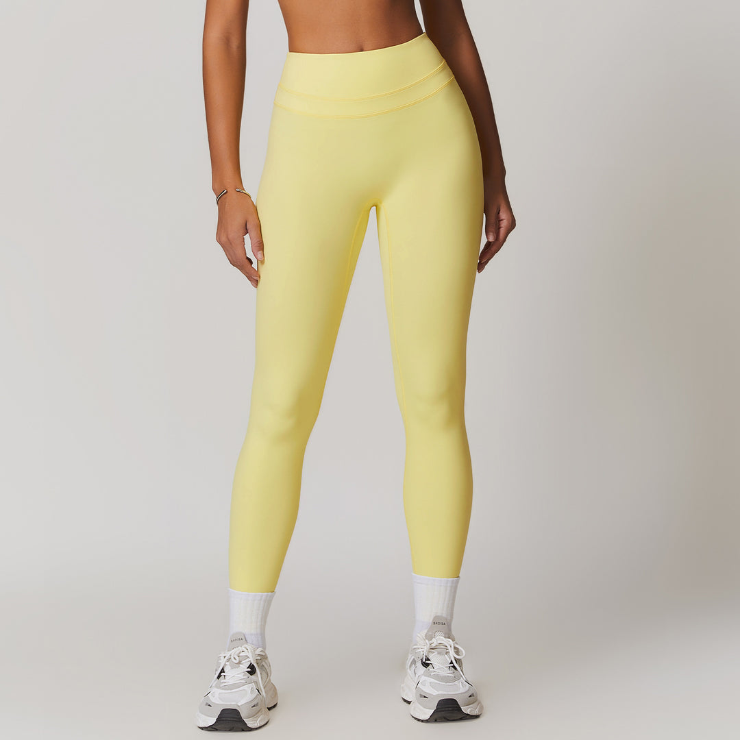 Person wearing yellow leggings and white sneakers on a plain background