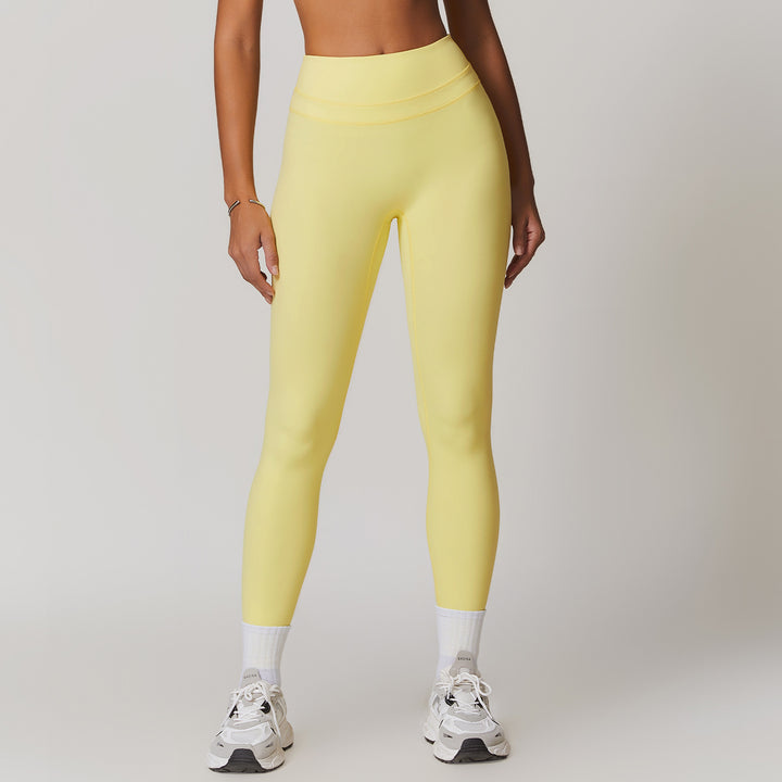 Person wearing yellow leggings and white sneakers on a plain background