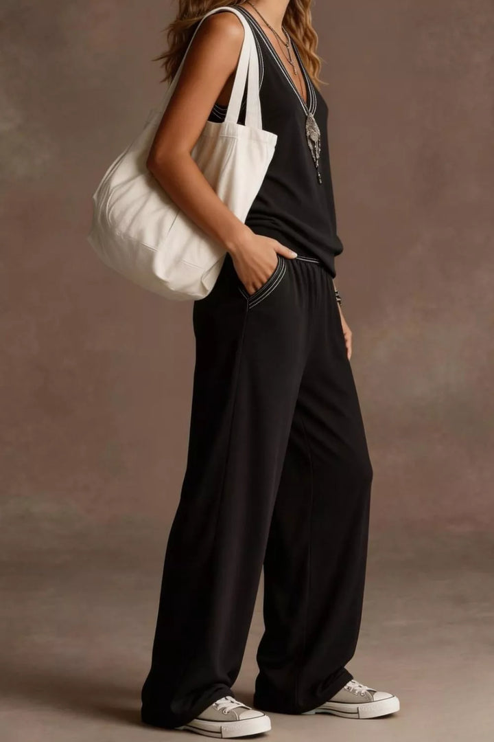 Person wearing a black outfit with a white bag against a neutral background