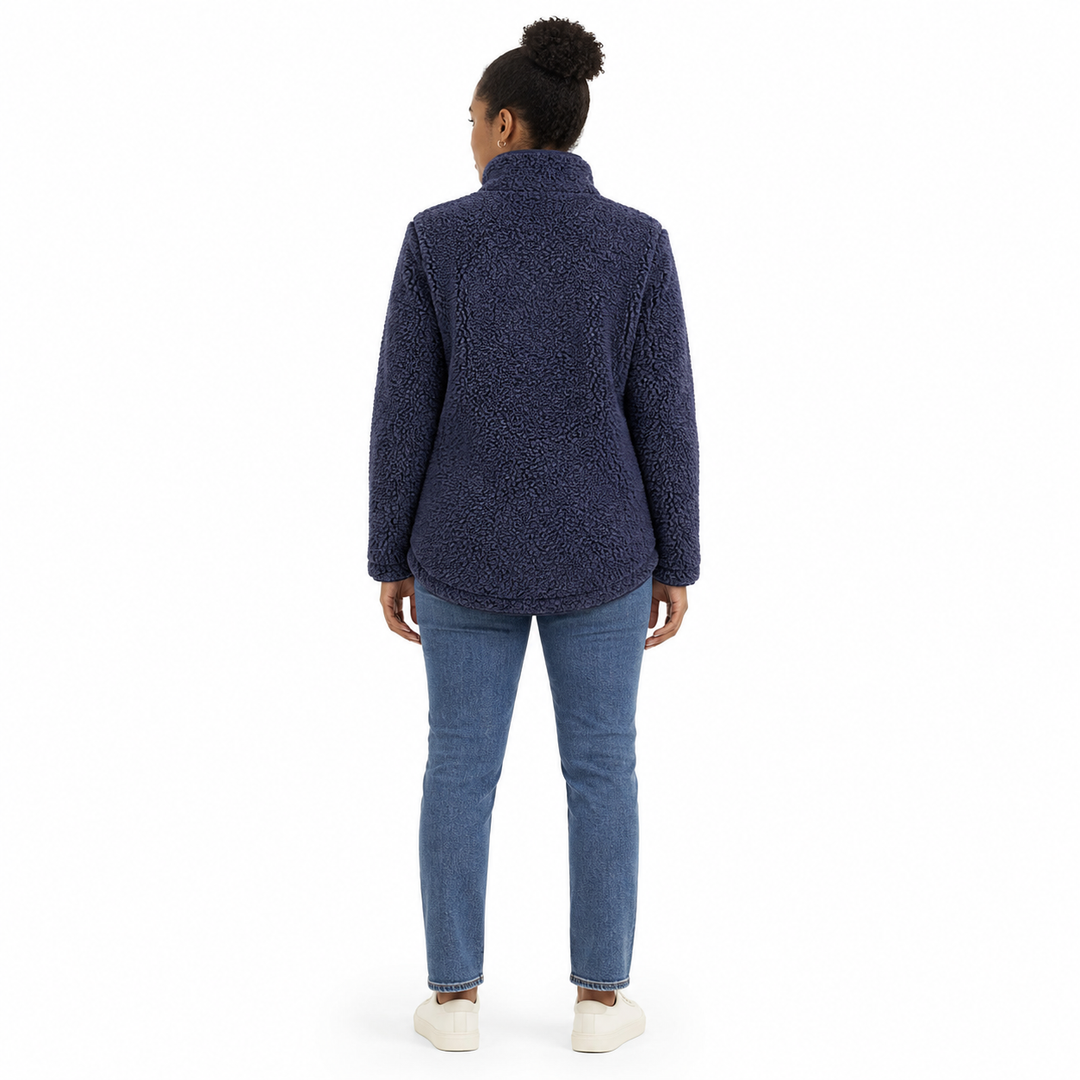 A woman viewed from the back wearing a textured navy blue fleece jacket, blue jeans, and white slip-on shoes against a plain white background.