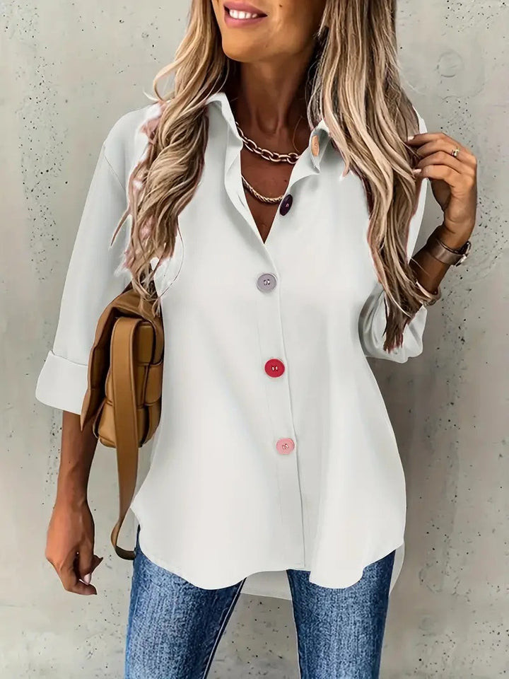 Woman wearing a white button-up shirt and blue jeans against a neutral background