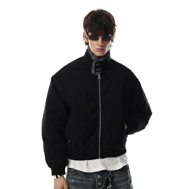 Black winter jacket on a male model with the collar raised, front zip fastened, long sleeves and gathered cuffs against white