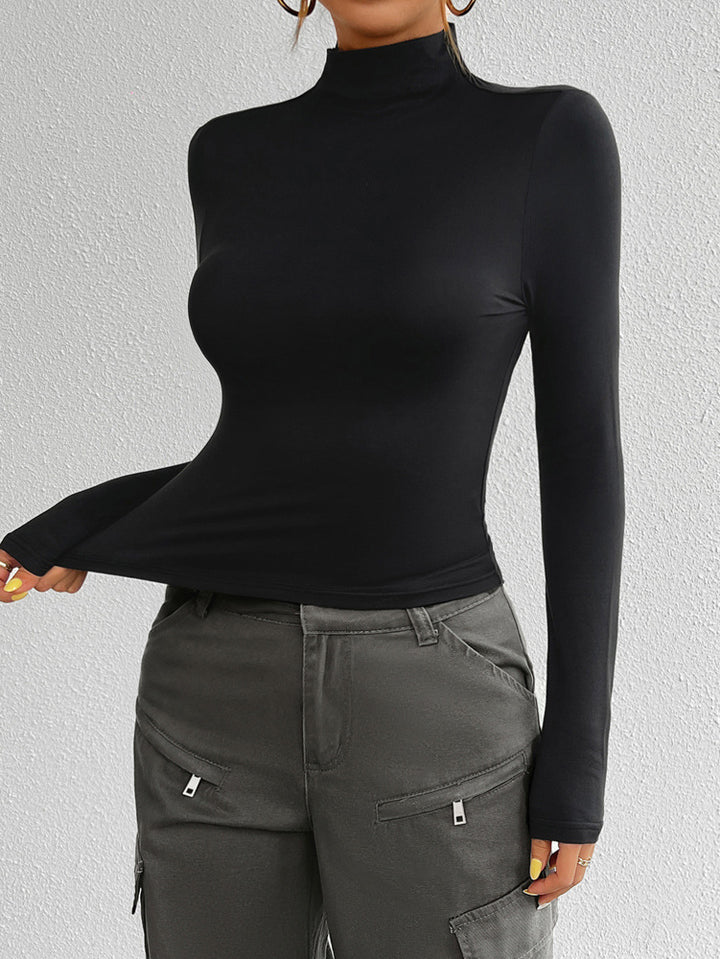 Person wearing a black turtleneck and gray cargo pants against a light gray background