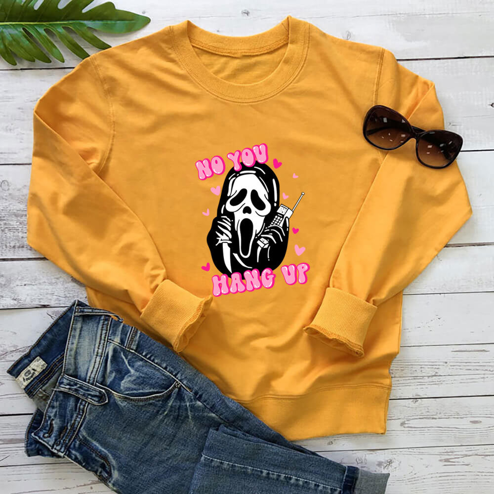 Yellow printed crewneck sweatshirt laid flat beside jeans and sunglasses photographed for comparing the photographed details.