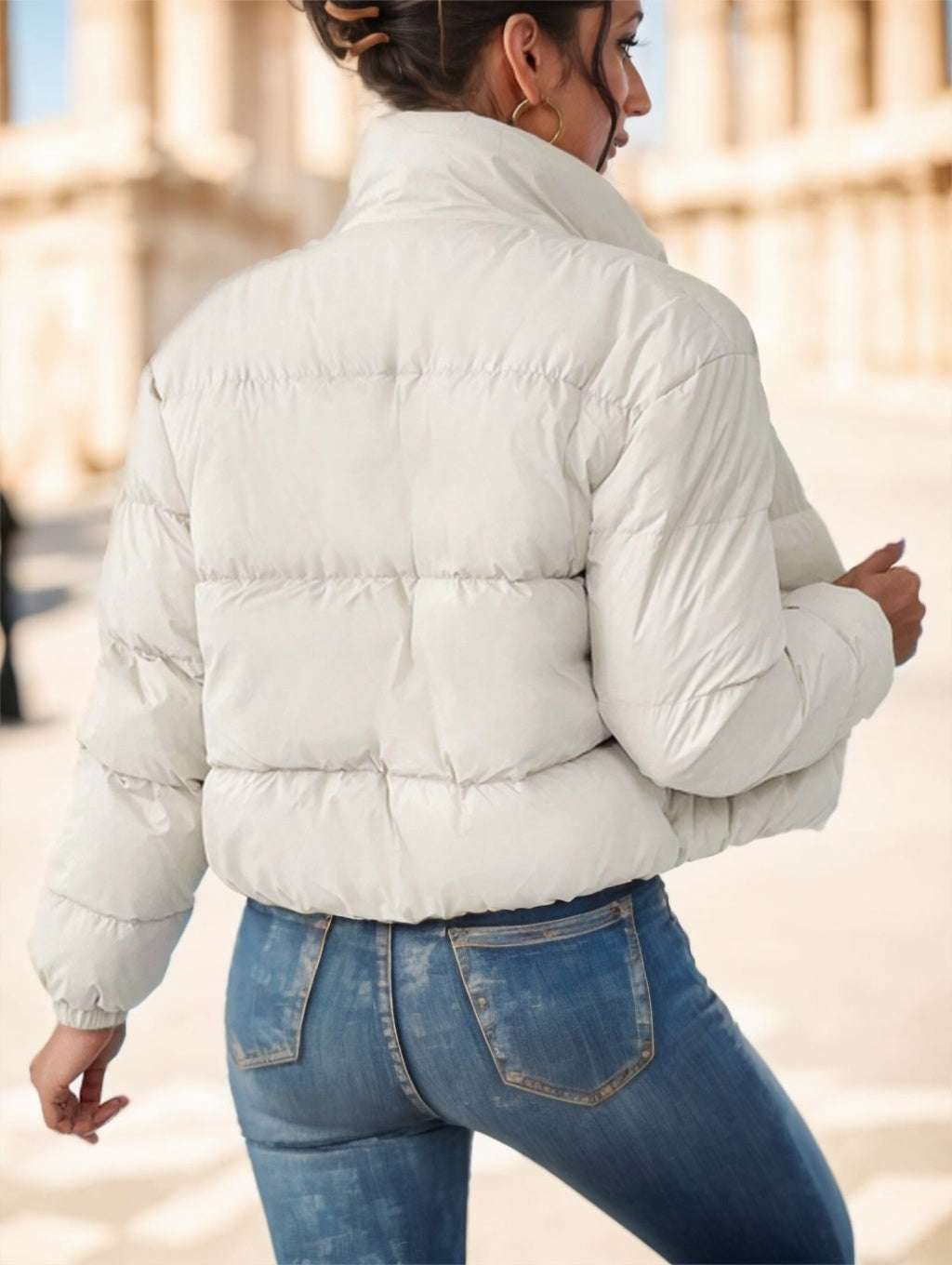 Woman modeling reversible puffer jacket in snowy setting

