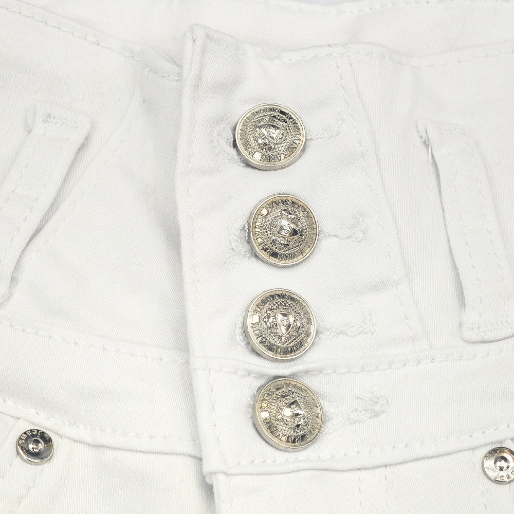 Detail view of rhinestone pocket and high-rise waistband of white shorts

