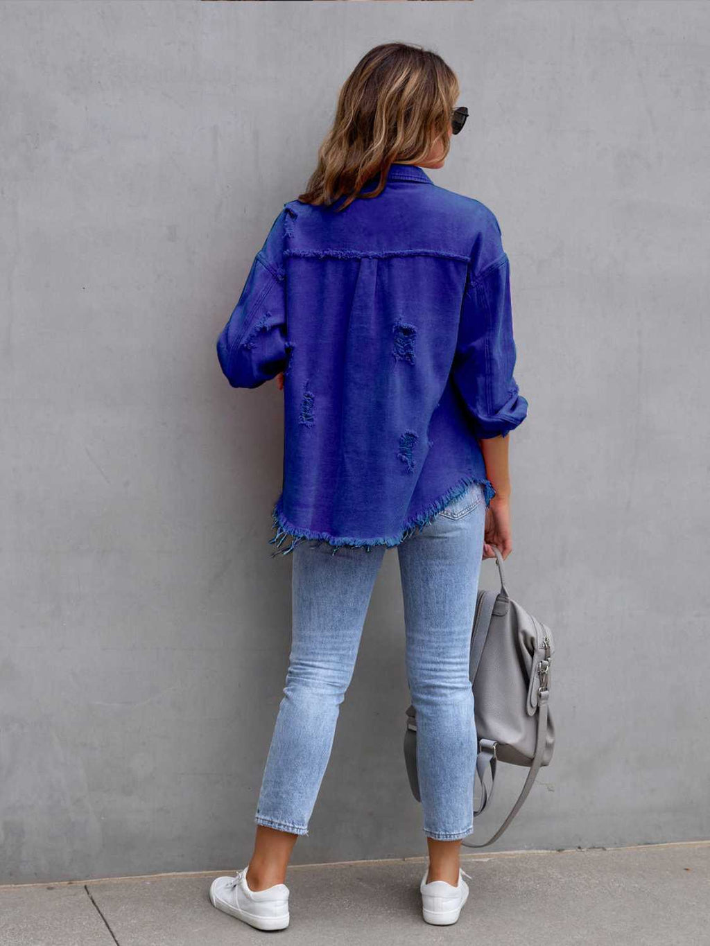Distressed denim jacket – detail shot of seams, pockets, and fringe