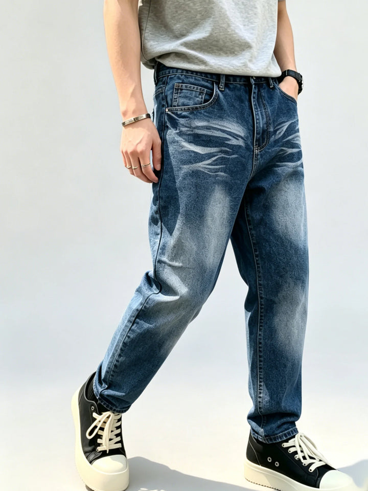 Front three-quarter view of blue loose straight-leg jeans showing pale whisker washing, front pockets and faded thigh panels.