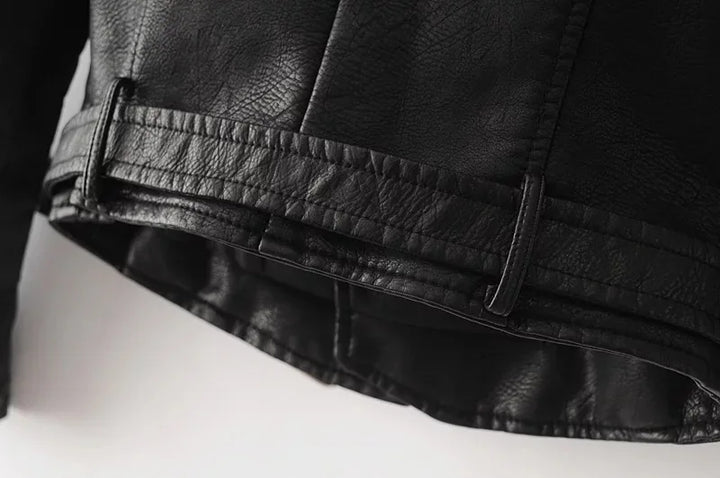 Close-up of the black jacket back hem, showing the stitched panel seams, the matching lower band and the textured outer side.