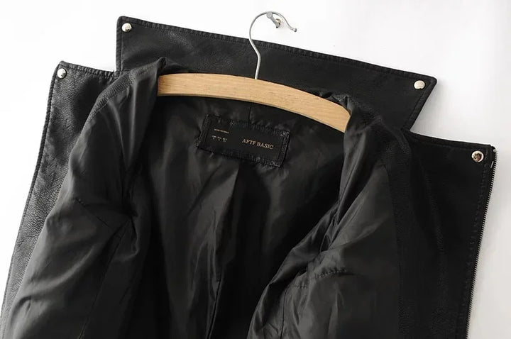 Black jacket interior view beneath an open collar, with the hanger, lining, shoulder tabs and snap details visible at the top