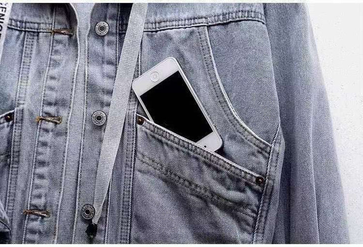 Large curved front pockets of the washed blue denim jacket holding a phone, with contrast stitching, metal buttons and rivet.