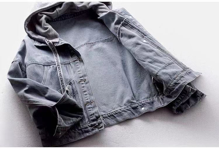 Open blue denim jacket laid flat, showing its inside, grey hood, long sleeves, printed drawstring and a metal button placket.