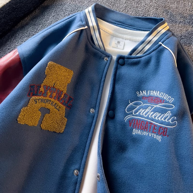 WT167 jacket in Blue shown in a close front view with sleeve embroidery and fabric details visible, on a gray fabric surface.